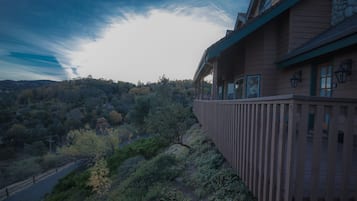 A wooden building with a balcony overlooking a forested hillside.