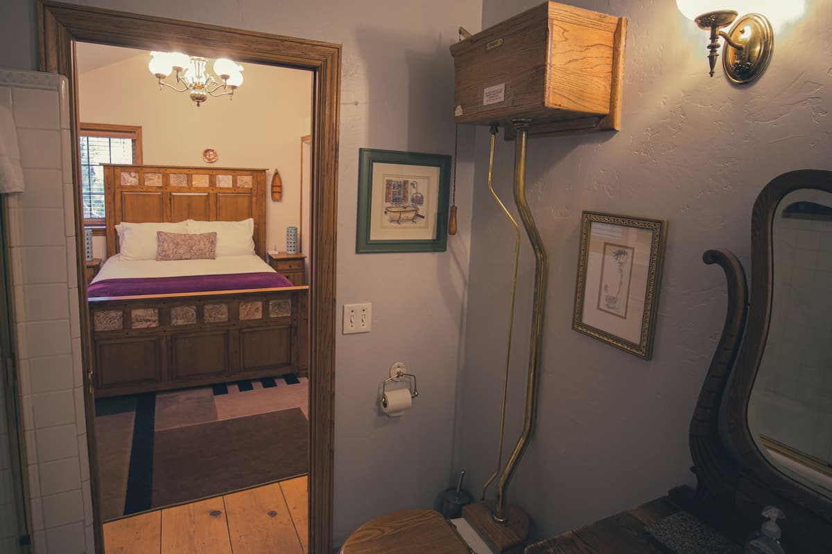 A bedroom with a wooden bed, a chandelier, and a wooden cabinet.