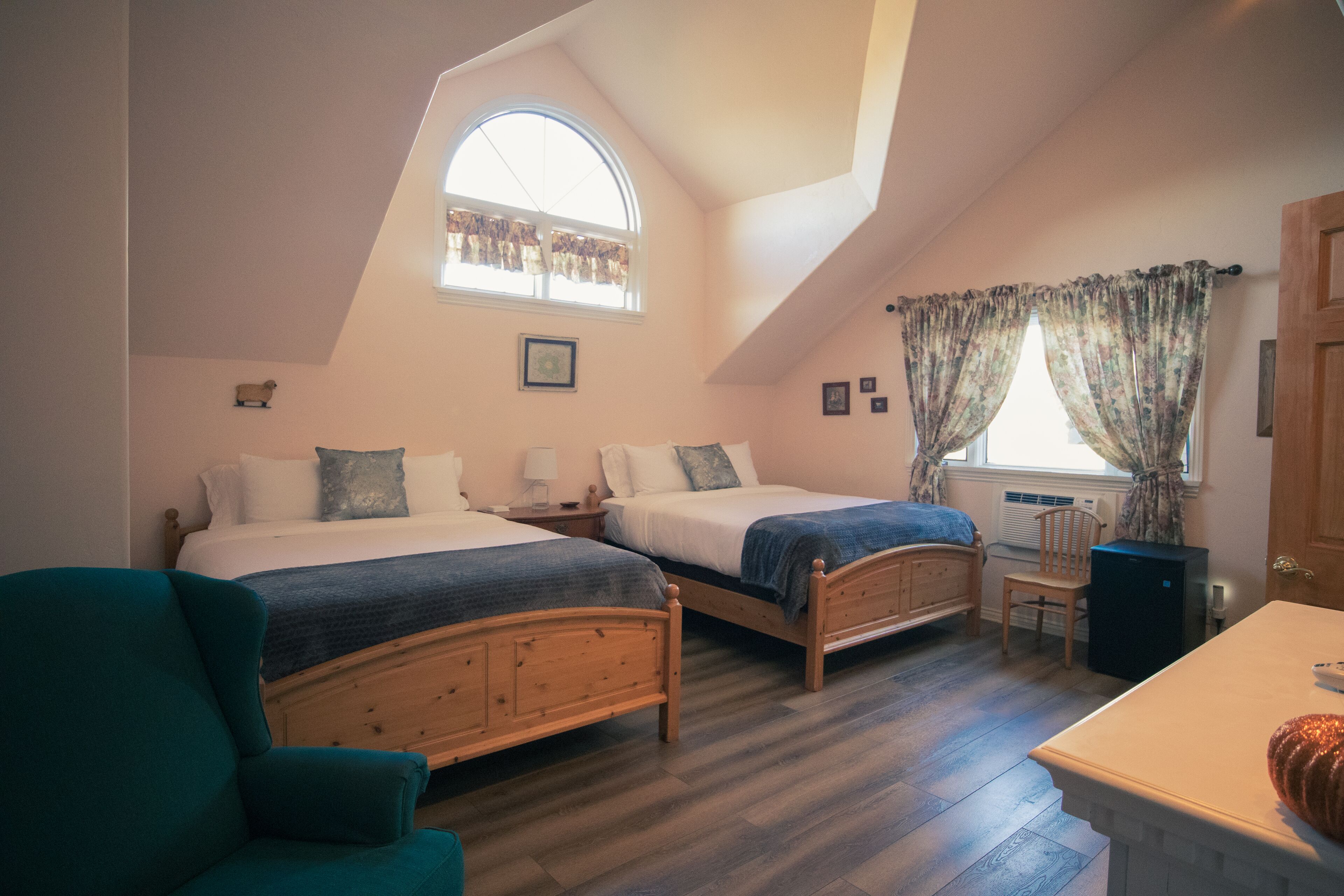 A bedroom with two wooden beds, a desk, a chair, and a window with curtains.