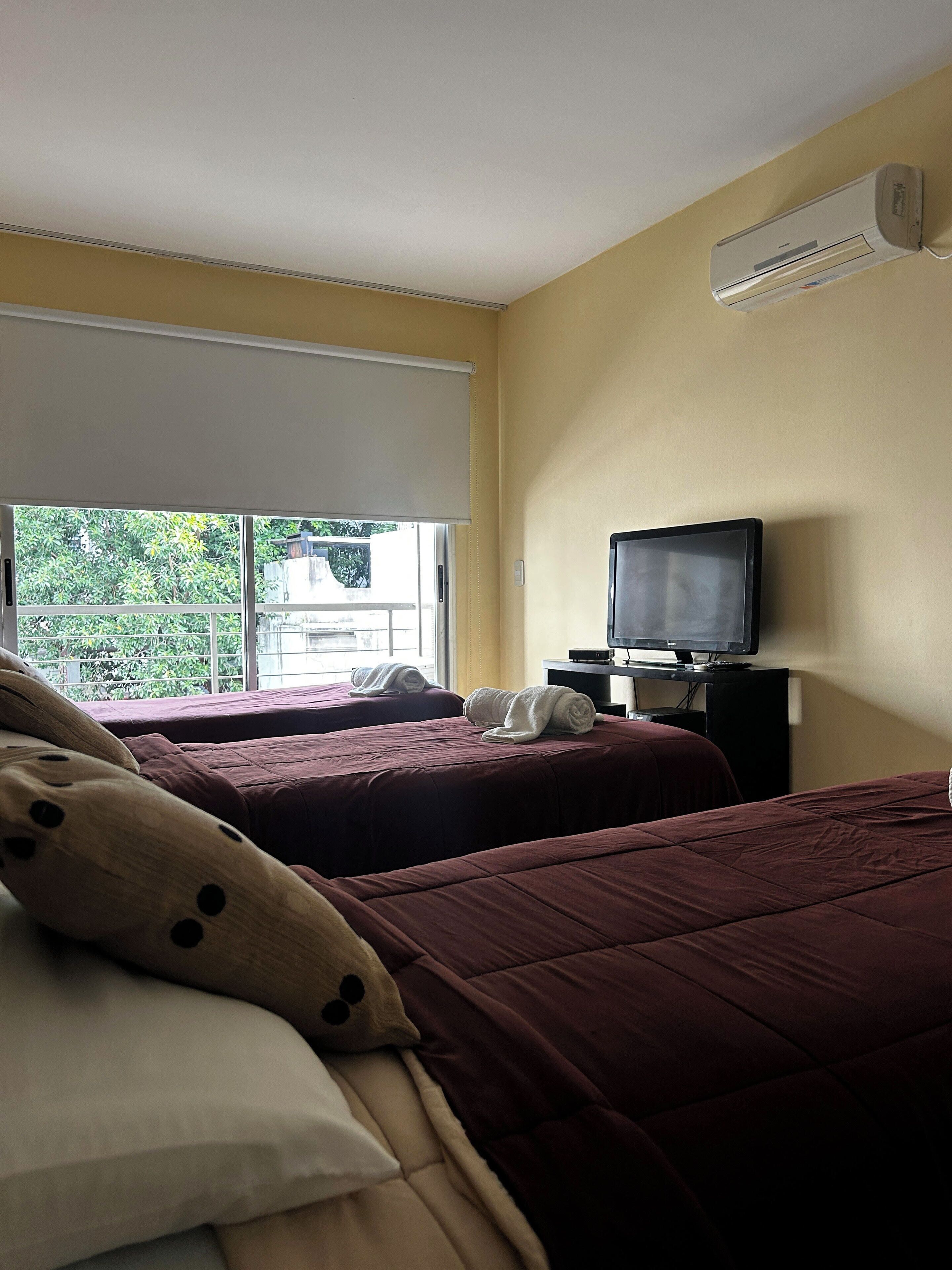 Een hotelkamer met twee bedden, een televisie en een airconditioner.