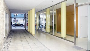 A corridor with a tiled floor, glass doors, and a brick wall. - Arenales Suites (Buenos Aires)
