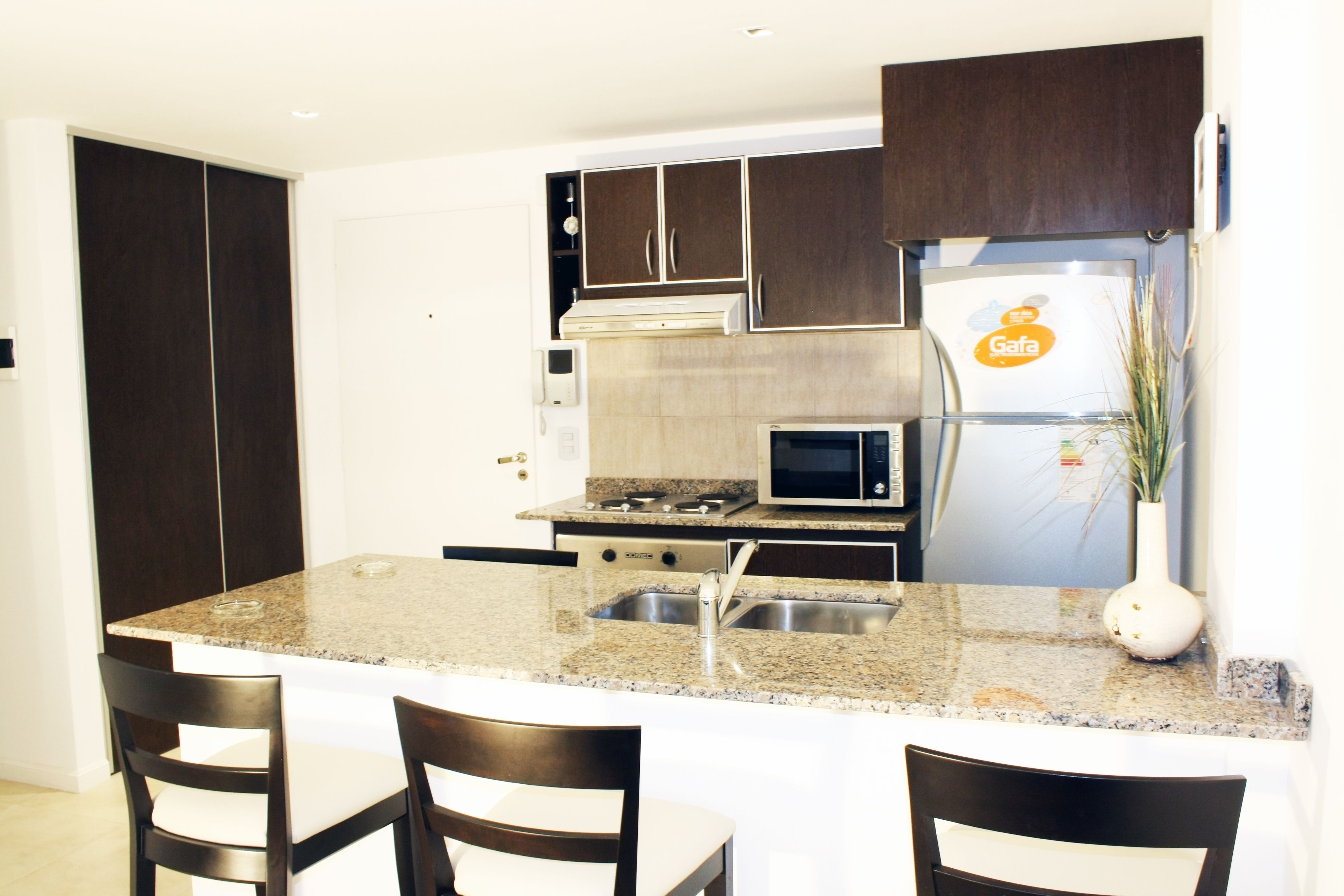 A modern kitchen with granite countertops, stainless steel appliances, and dark wooden cabinets.