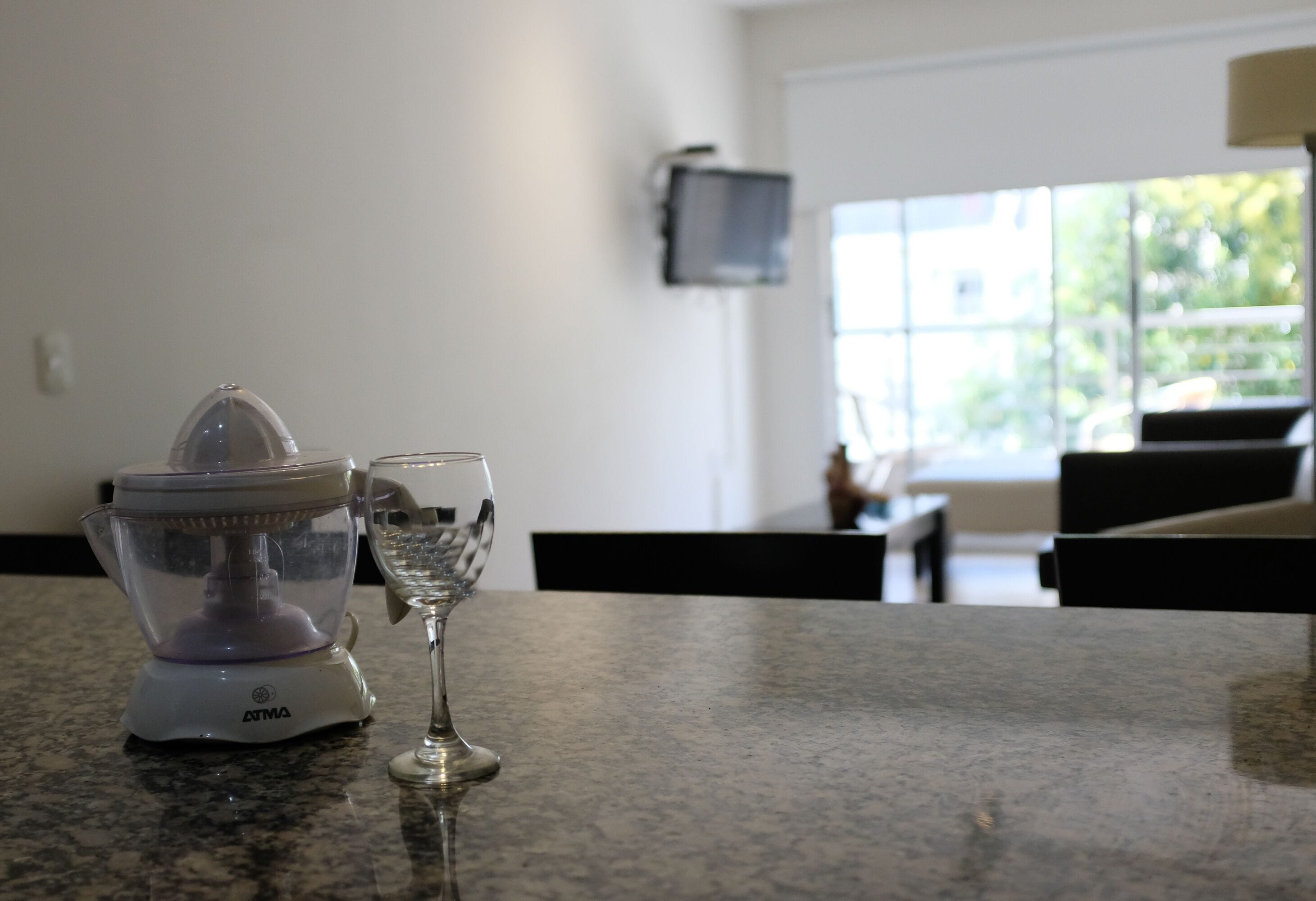 A kitchen counter with a food processor and a wine glass.