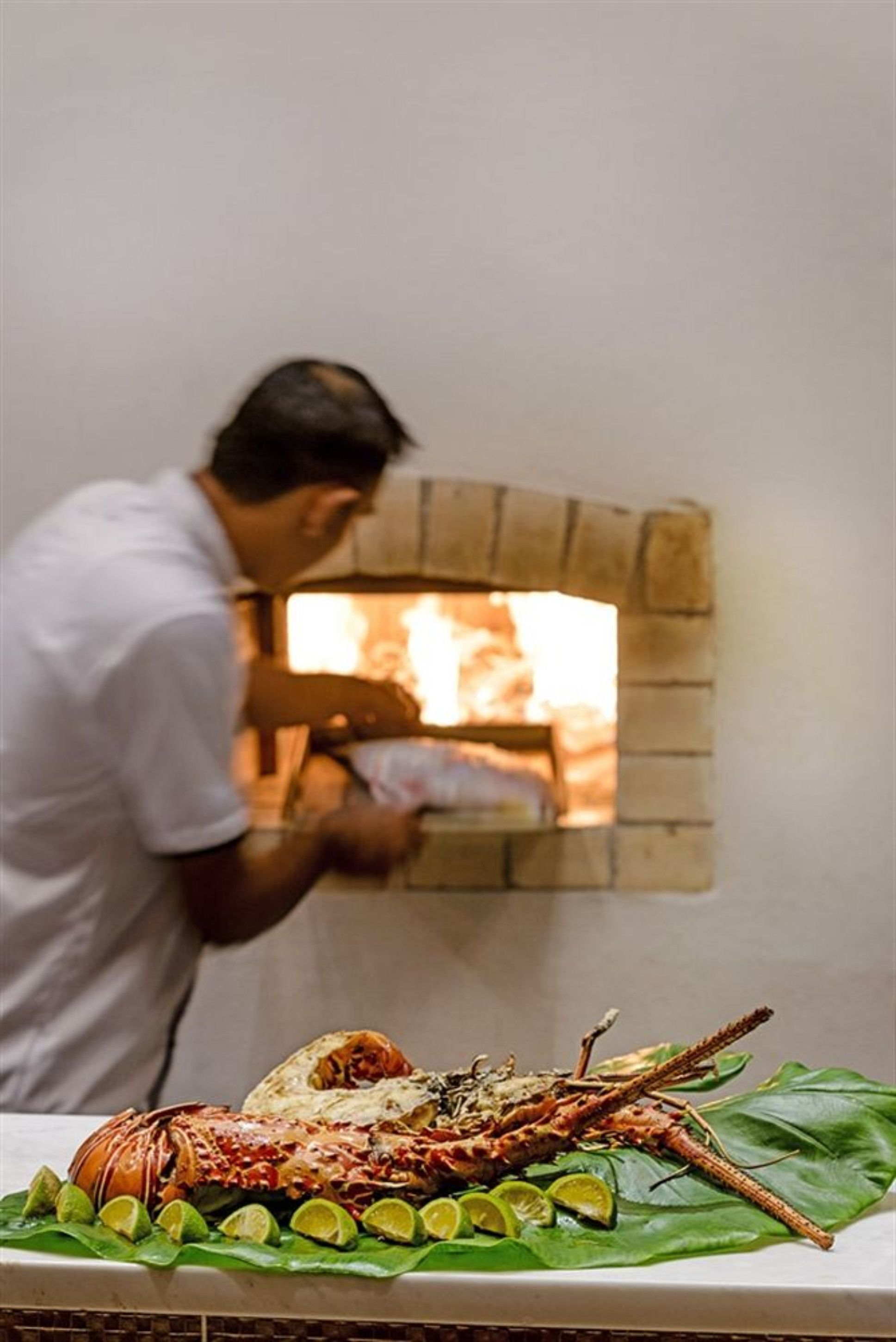 Una persona preparando comida en un horno de ladrillo.