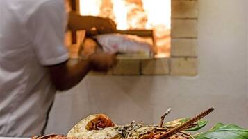 Una persona preparando comida en un horno de ladrillo.