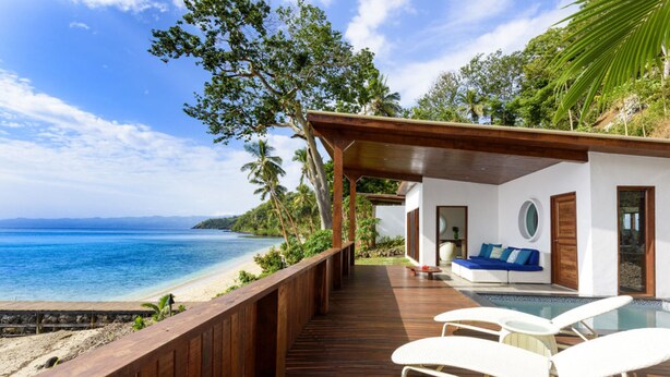A wooden deck with white lounge chairs overlooking a beach. - The Remote Resort, Fiji Islands (Nawi)