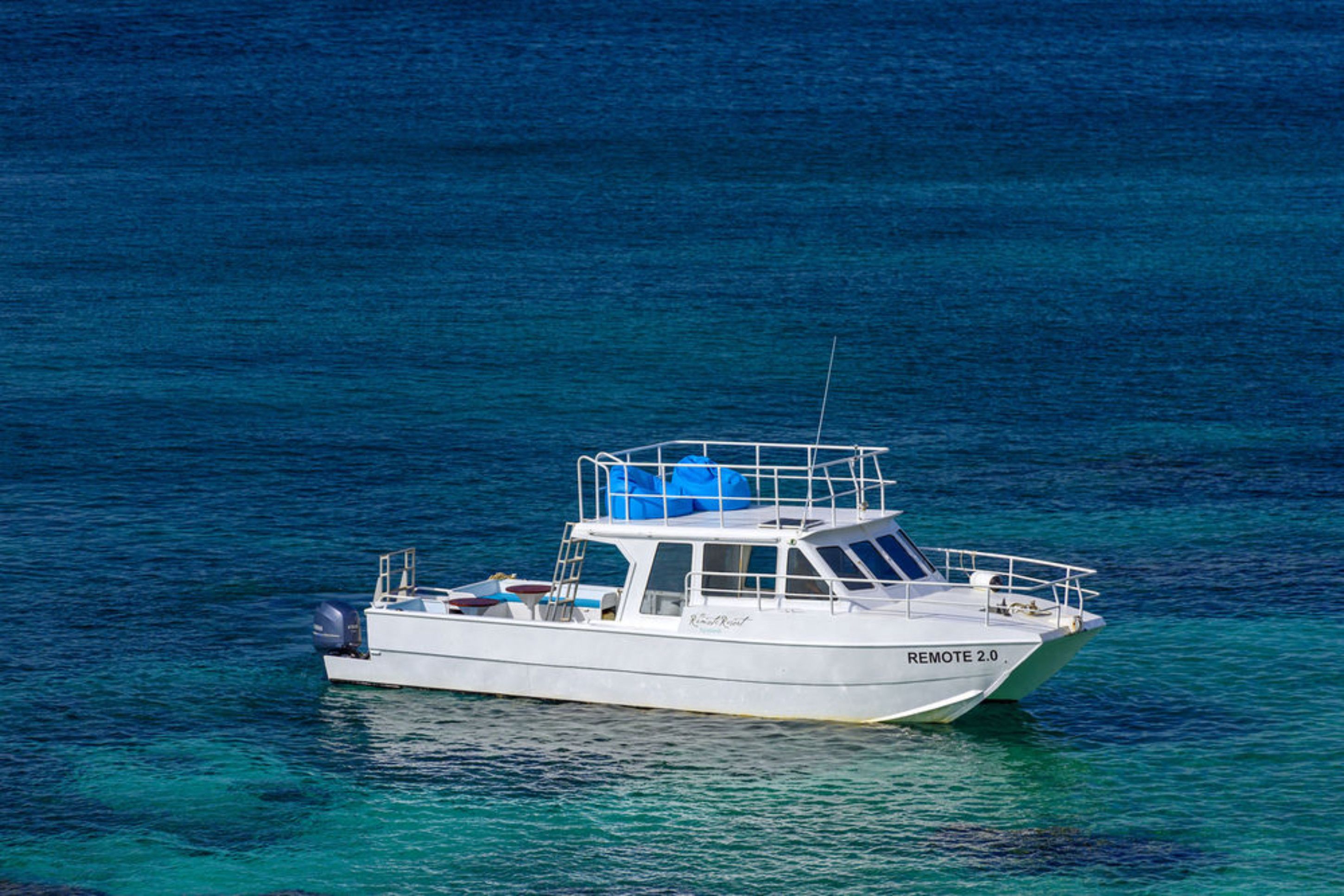 Un petit bateau blanc, baptisé « REMOTE 2.0 », navigue sur une eau d’un bleu limpide.
