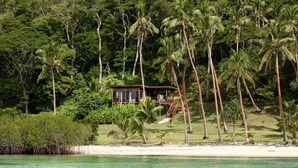 A beachside property with a wooden structure surrounded by palm trees and dense foliage. - The Remote Resort, Fiji Islands (Nawi)