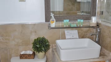 Une salle de bain avec des toilettes blanches, un lavabo avec un miroir et un espace douche.