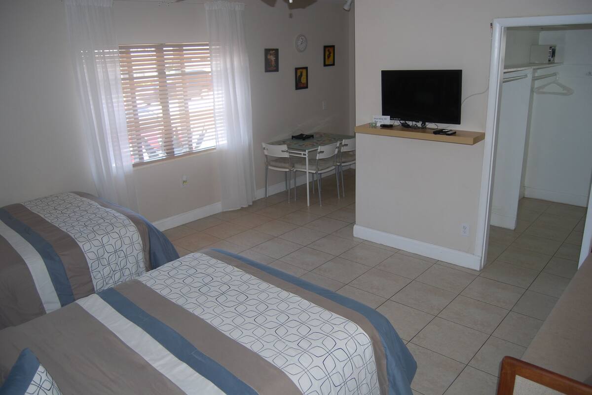 A room with two beds, a desk, a television, and a closet.