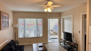 A living room with a ceiling fan, a TV on a wooden stand, a sofa, and a table.
