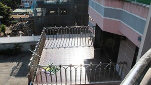 A balcony with a metal railing, a tiled floor, and a view of the surrounding buildings.