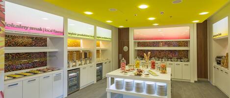 A brightly lit food display area with various food items and a beverage dispenser.