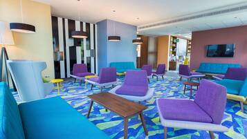 A modern lounge area with colorful seating and a patterned carpet.