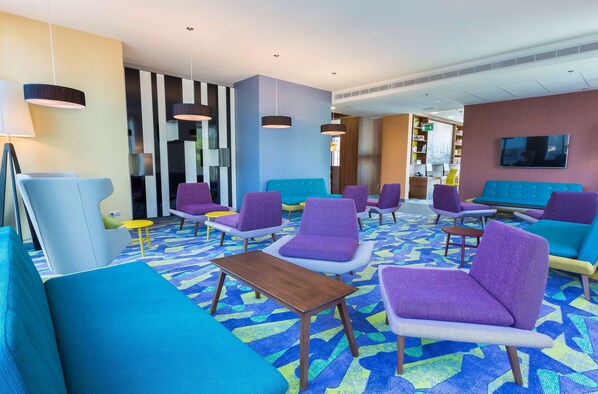 A modern lounge area with colorful seating and a patterned carpet.