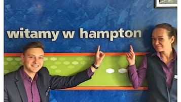 Dos personas señalando un letrero que dice "witamy w hampton".