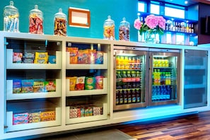 Exhibición de aperitivos con diferentes productos envaselados y una sección refrigerada para bebidas.