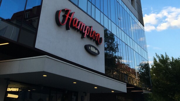 Un hôtel moderne, reconnaissable à son enseigne bien visible « Hampton by Hilton ».