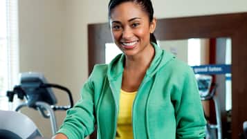A person sitting on a treadmill in a gym with exercise equipment in the background.
