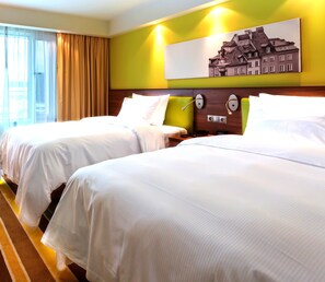 Een hotelkamer met twee bedden, een groot raam met gordijnen, een schilderij aan de muur en een nachtkastje met een lamp.