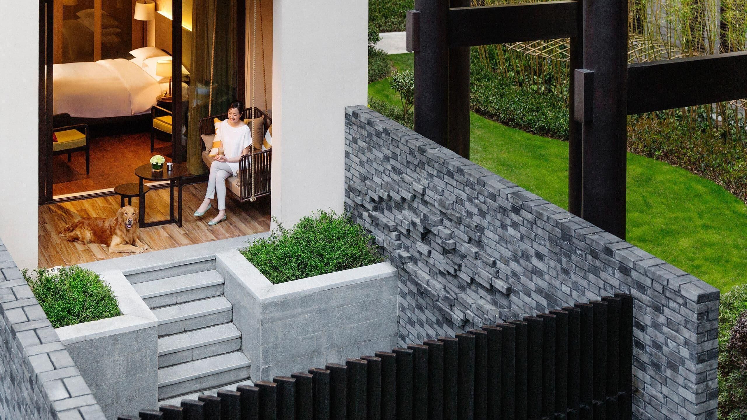A modern hotel room with a bed, a sitting area, and a view of the garden.