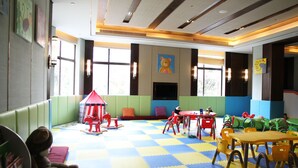 Un'area giochi per bambini con tappetini colorati, giocattoli e posti a sedere.