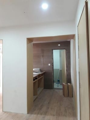 A hallway with a wooden desk, a mirror, and a door leading to another room.