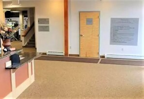 A reception area with a reception desk, a wooden door, and a wall-mounted sign.