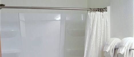 A bathroom with a glass-enclosed shower, a toilet, and a towel rack.