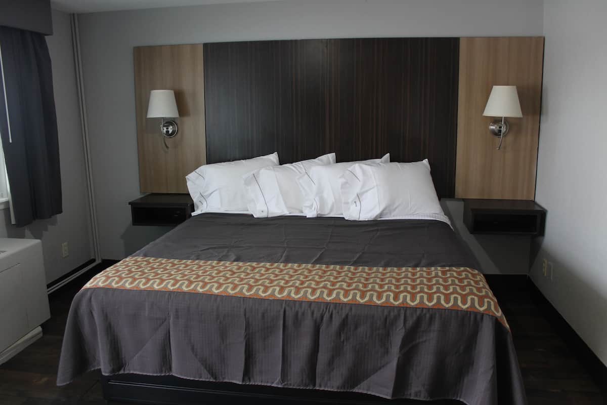 A hotel room with a large bed, two bedside tables, and two wall-mounted lamps.