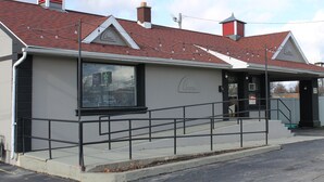 Un bâtiment doté d’un toit recouvert de tuiles rouges, d’une rambarde noire et d’un escalier menant à une porte.
