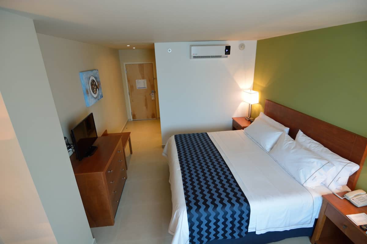 Une chambre d’hôtel équipée d’un lit, d’une table de chevet, d’une lampe et d’un bureau avec un ordinateur.