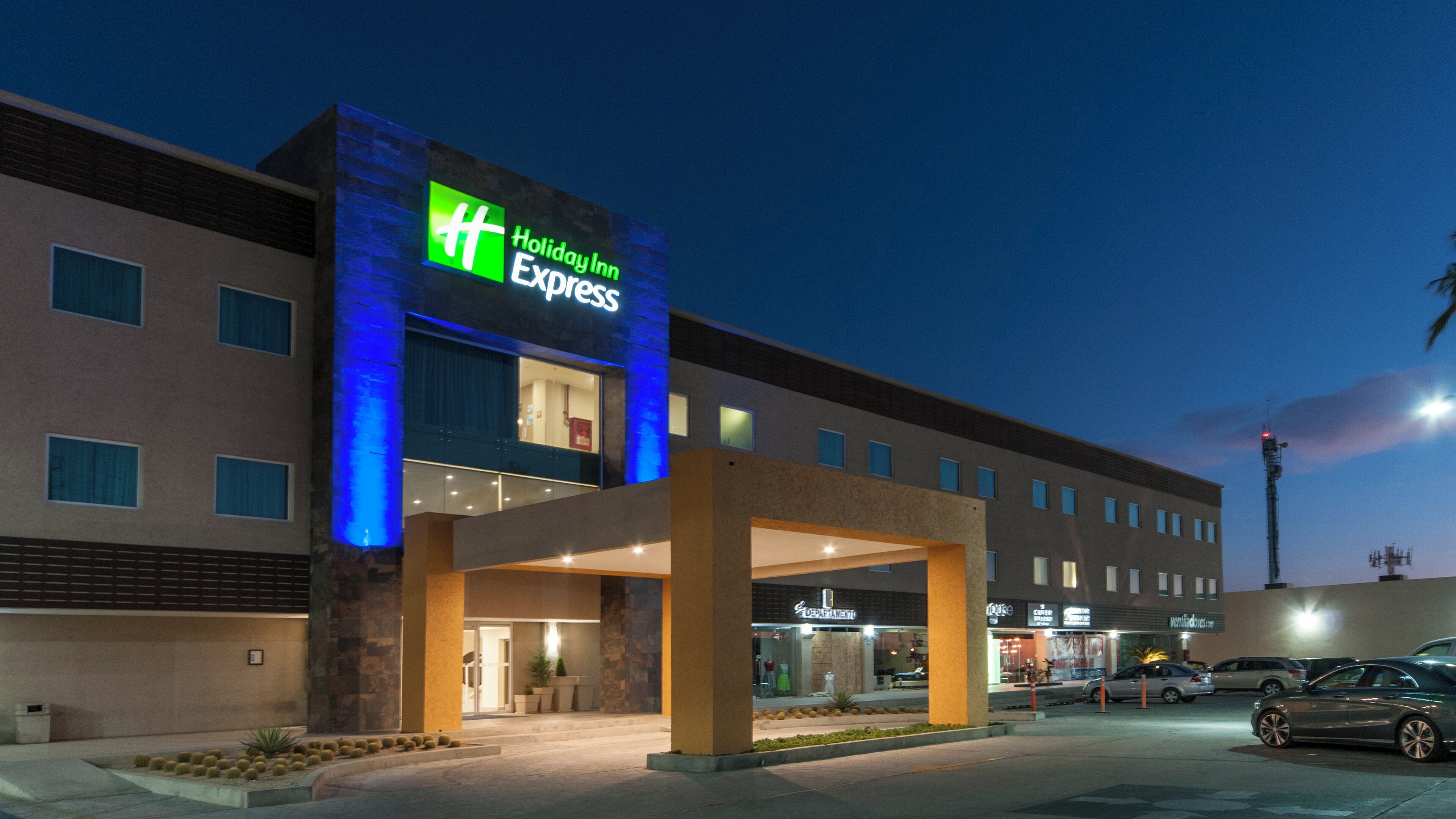 A Holiday Inn Express hotel with a modern facade, a visible entrance, and a parking area in front.