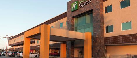 A Holiday Inn Express hotel with a covered entrance, a parking lot, and adjacent businesses.