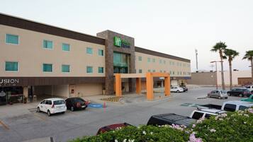 A Holiday Inn Express hotel with a parking lot, several cars, and palm trees in the background.