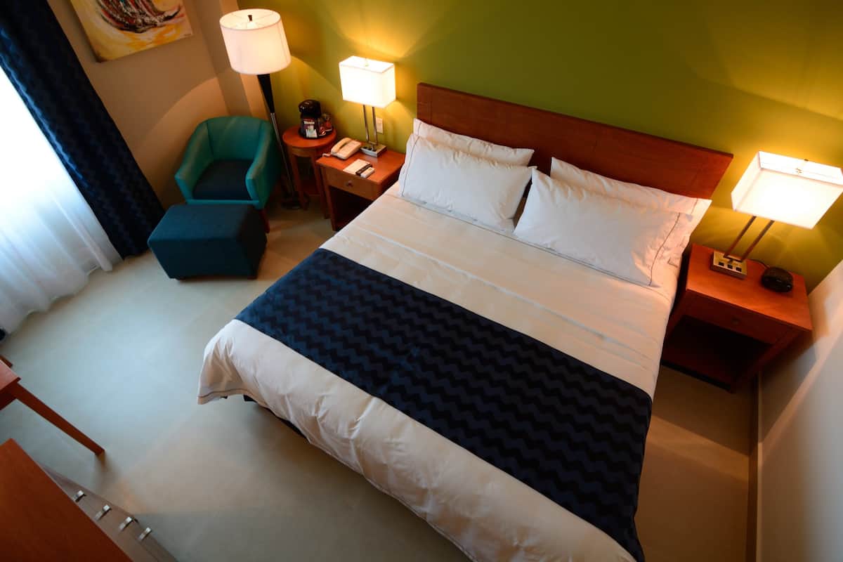 Une chambre d’hôtel avec un grand lit, deux tables de chevet, une chaise et une lampe.