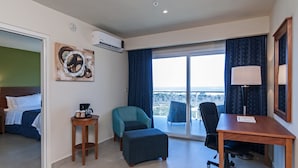 Une chambre d’hôtel avec un lit, un bureau, une chaise, une petite table et un balcon avec vue.