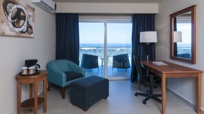 A hotel room with a balcony, a desk, a chair, a coffee maker, and a lamp. - Holiday Inn Express Cabo San Lucas by IHG (Cabo San Lucas)