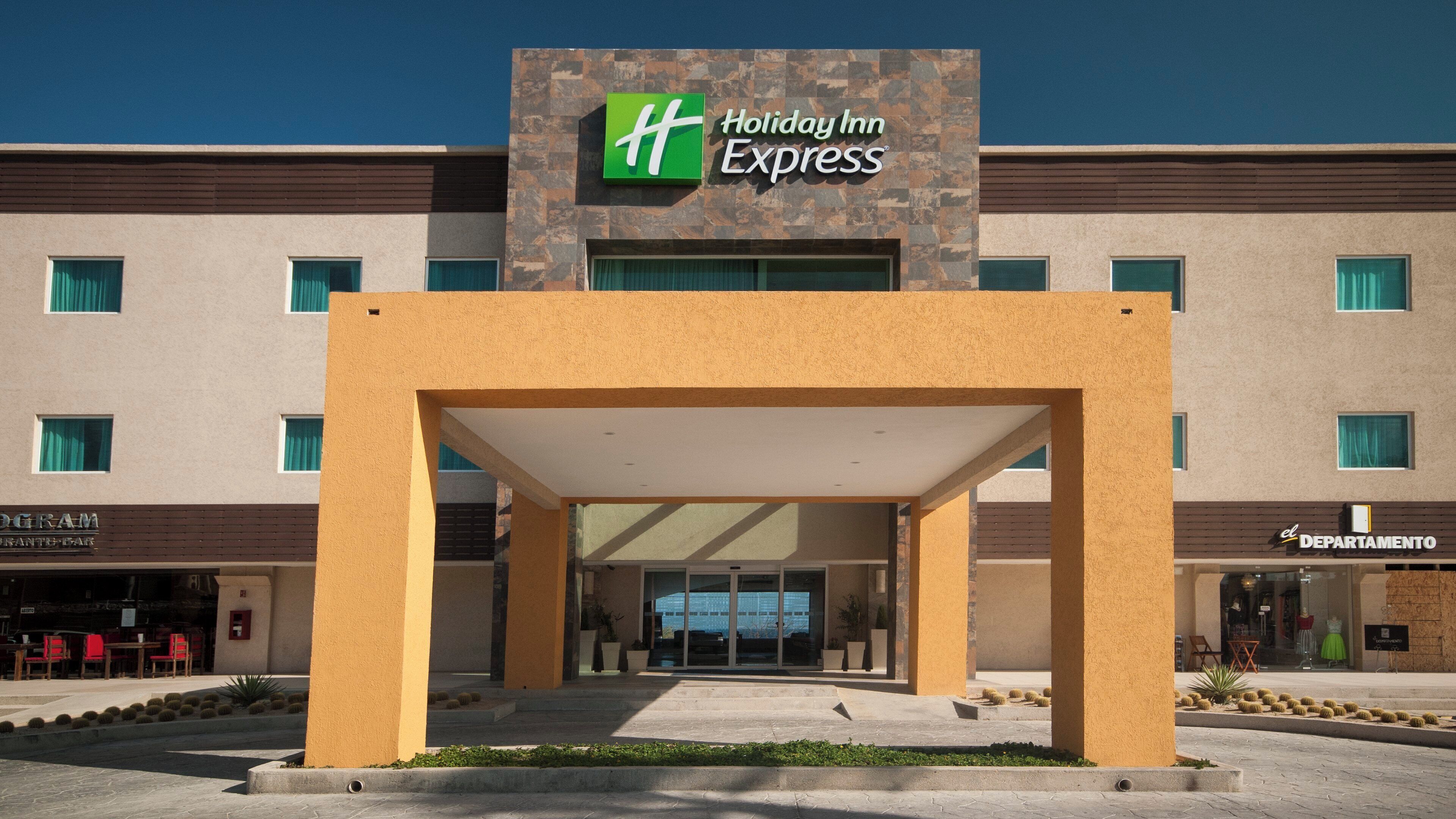 A Holiday Inn Express building with a modern facade, a covered entrance, and a visible parking area.