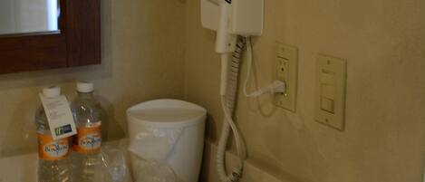 A bathroom with a toilet, a hand dryer, and a tissue box on the counter.