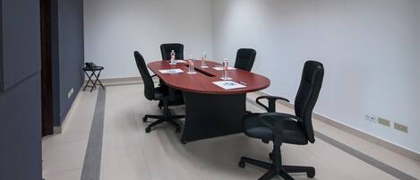 A conference room with a rectangular table, four black chairs, and water bottles on the table.