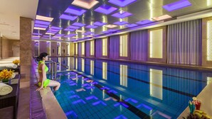 A swimming pool with a tiled floor and a person sitting by the pool. - Grand Skylight International Hotel Guiyang (Guiyang)
