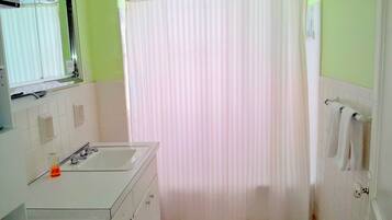 A bathroom with a white sink, mirror, and a shower curtain.