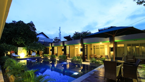 A pool area with lounge chairs and a wooden deck. - Hotel Griya Asri (Mataram)