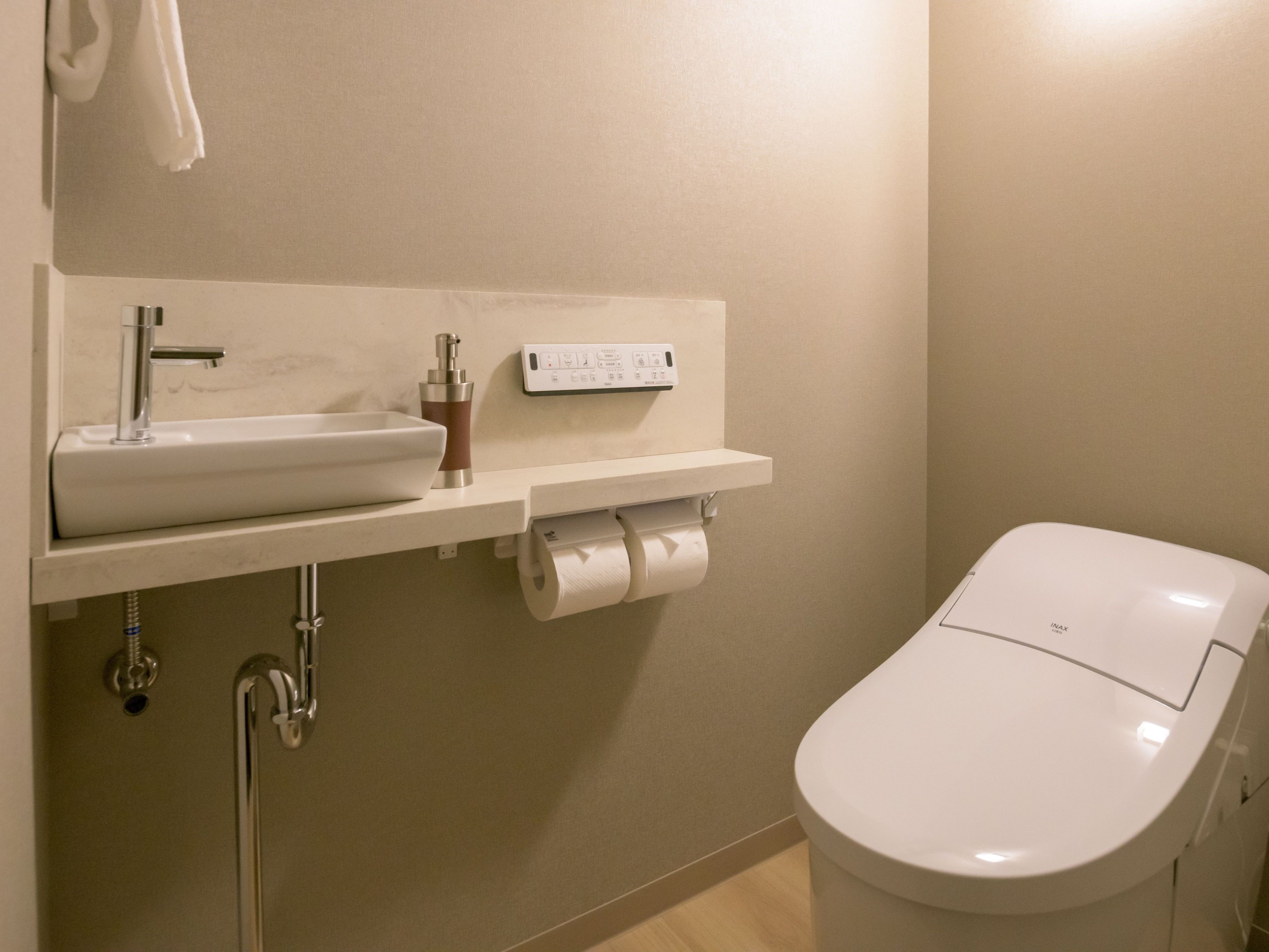 A bathroom with a white sink, faucet, and toilet paper dispenser.