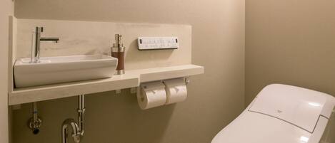 A bathroom with a white sink, faucet, and toilet paper dispenser.