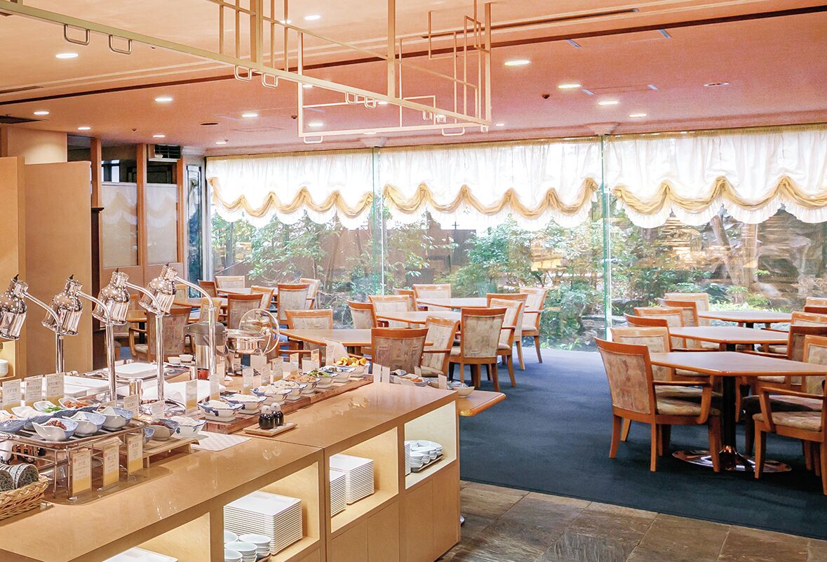 A restaurant with a buffet setup, multiple tables, and chairs arranged for dining.