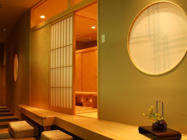 A traditional Japanese room with tatami flooring, a sliding door, and a round mirror on the wall. - Nara Royal Hotel (Nara)