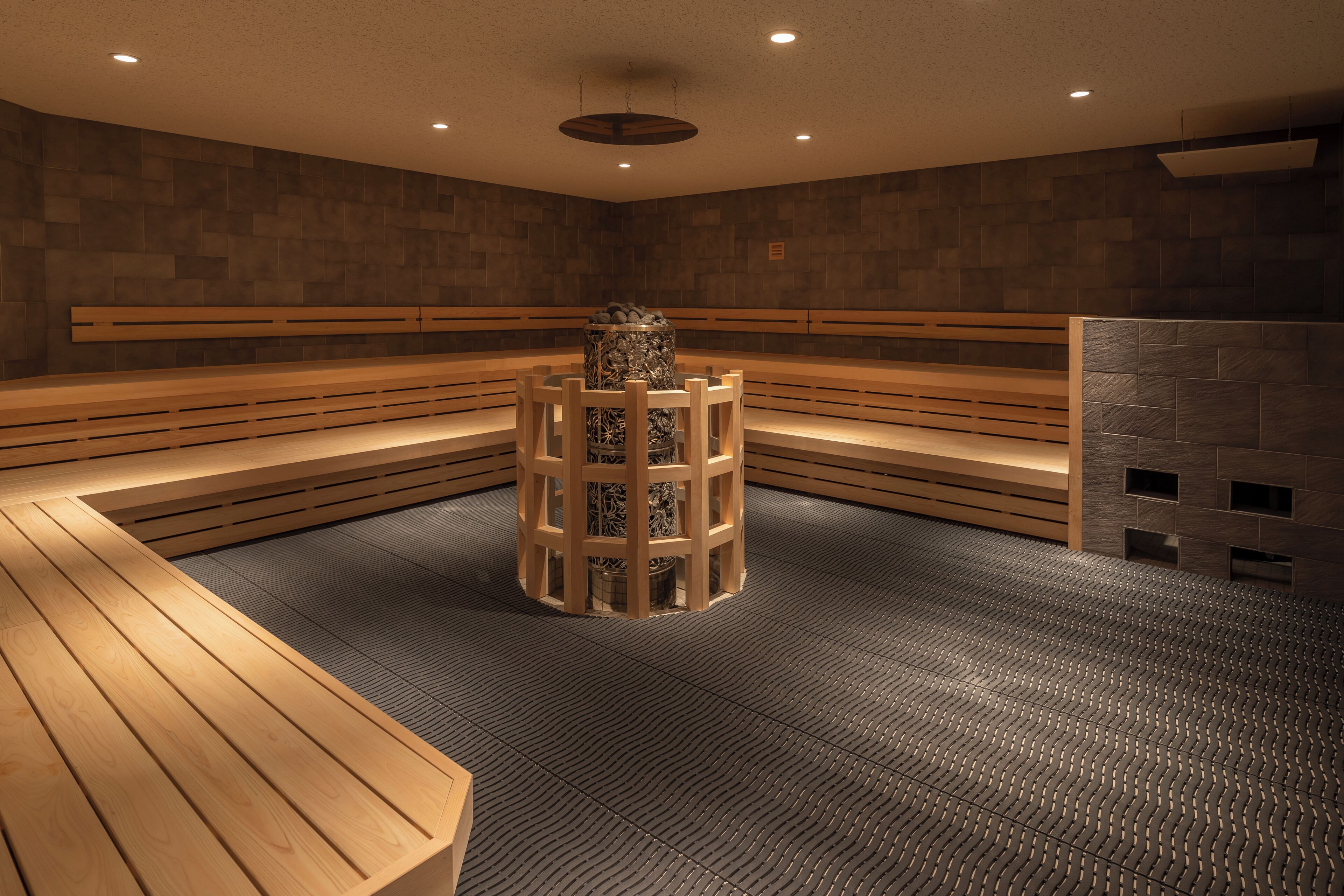 A sauna room with wooden benches and a central pillar.