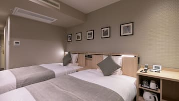 Ein Hotelzimmer mit zwei Betten, einem Nachttisch mit Kaffeemaschine, einer digitalen Uhr und einem Wandlüfter.